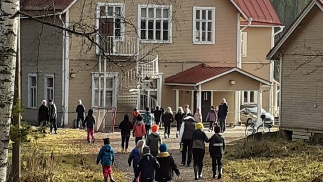 Lapsia vanhan puukoulun pihalla.