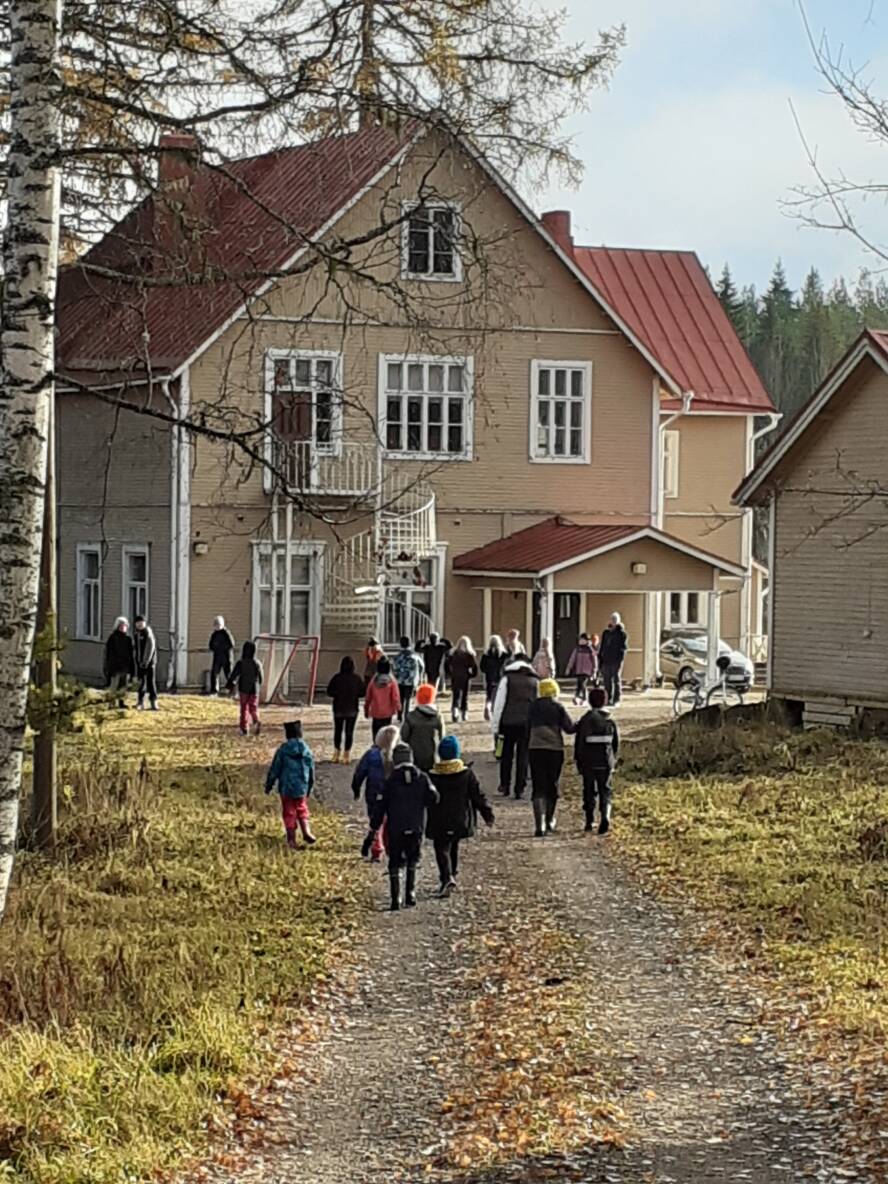 Lapsia vanhan puukoulun pihalla.
