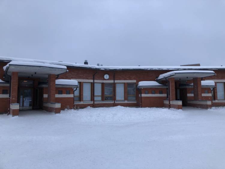Suonenjoen Yhtenäiskoulun sisäänkäyntejä. Kello seinällä näyttää 12.25. Pilvinen talvipäivä.