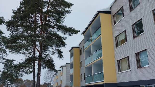 Kolem kerroksisen kerrostalon julkisivu kuvattuna sivusuunnasta. Näkyvissä ikkunoita ja parvekkeita.