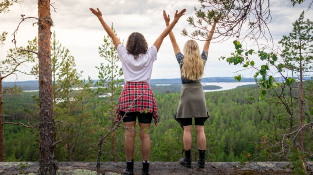 Kaksi naista seisoo kallion reunalla kädet ylhäällä Kalajanvuorella.