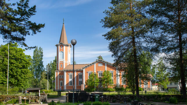 Suonenjoen oranssi puukirkko aurinkoisena päivänä.
