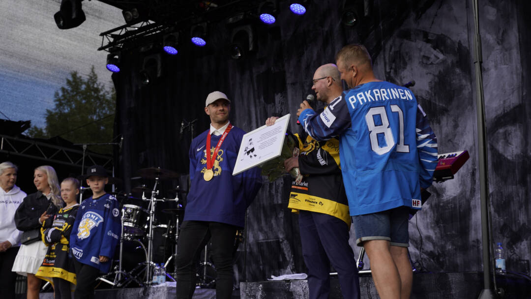 Kaupunginjohtaja Juhla Piiroinen pitelee kädessään laattaa. Iiro Pakarinen hymyilee olympiakultamitali kaulassaan.