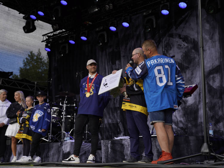 Kaupunginjohtaja Juhla Piiroinen pitelee kädessään laattaa. Iiro Pakarinen hymyilee olympiakultamitali kaulassaan.