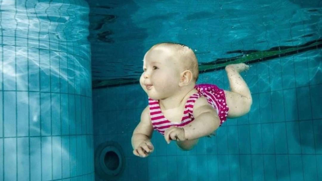 Vauva uimassa veden alla uima-altaassa.