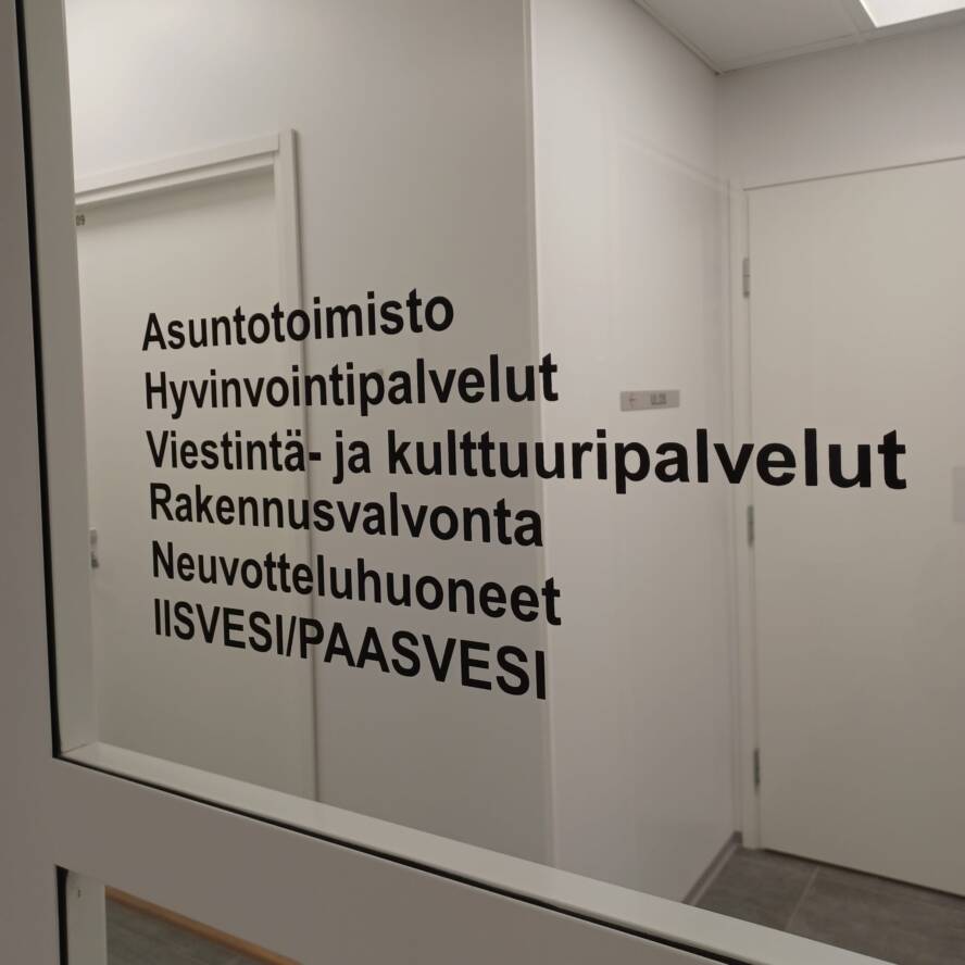 Virastotalon sisäoven ikkuna, jossa on tekstiä