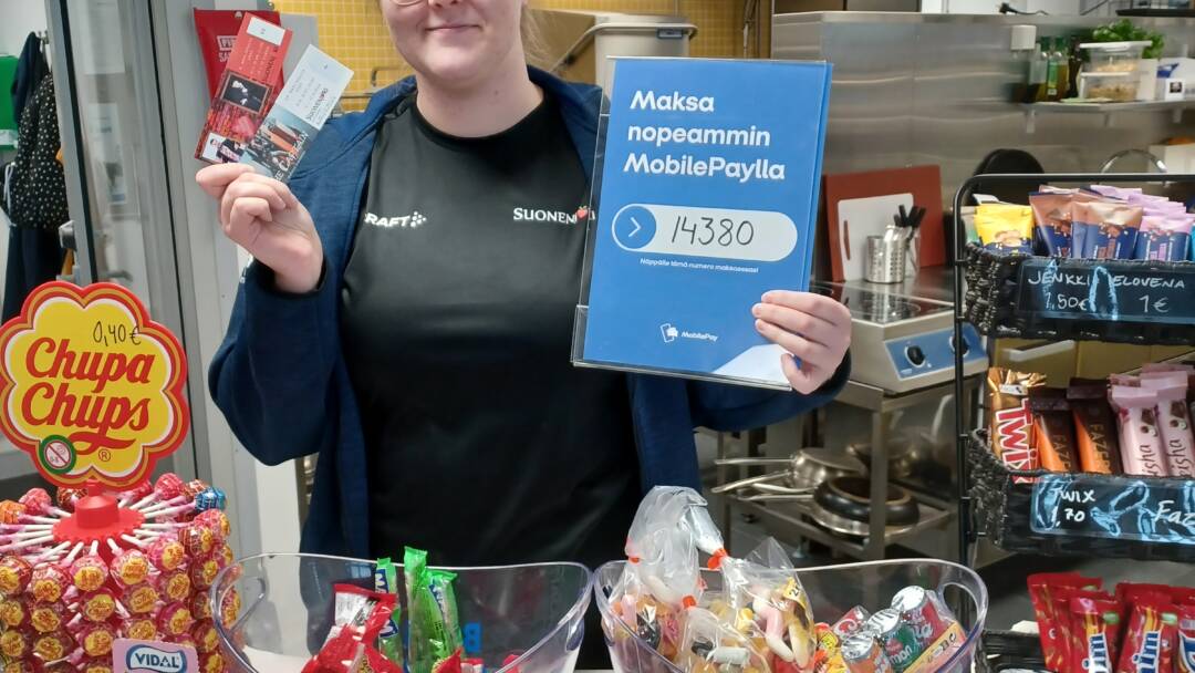 nainen esittelee pääsylippuja kahvion kassalla