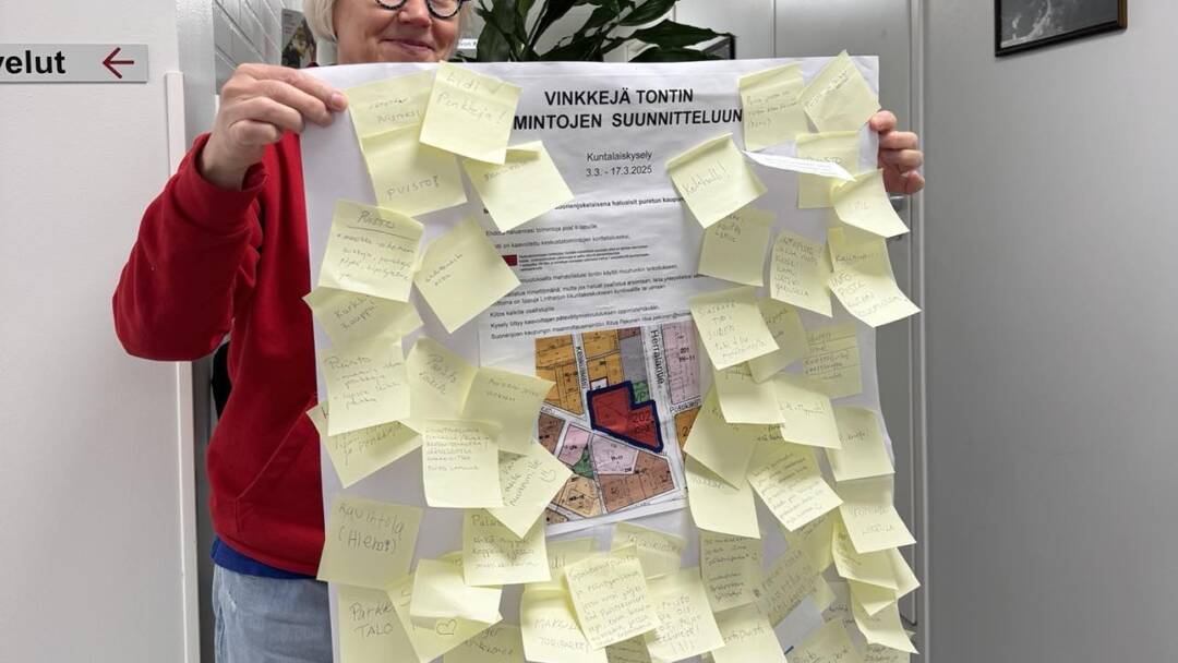 Ritva pitelee kädessään karttaa täynnä post-it lappuja