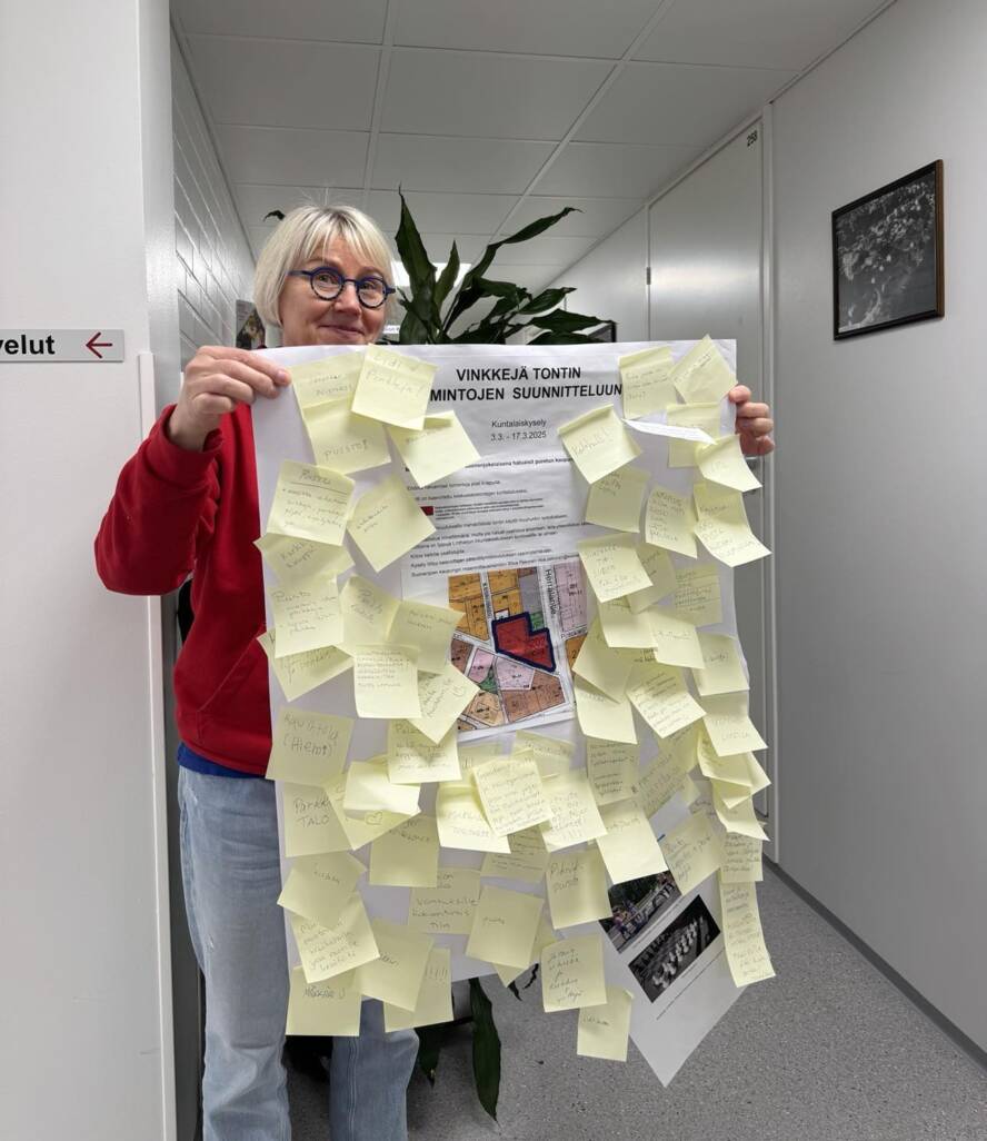 Ritva pitelee kädessään karttaa täynnä post-it lappuja