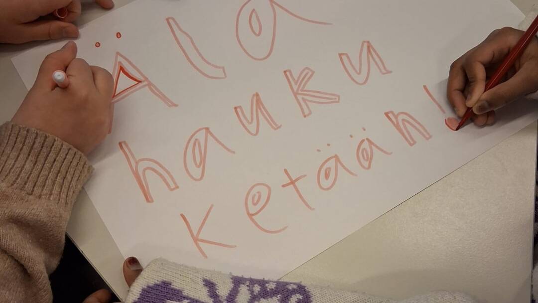 kahden lapsen kädet kirjoittavat lapulle älä hauku ketään. rasisminvastainen viikko koululla. suonenjoen yhtenäiskoulu.