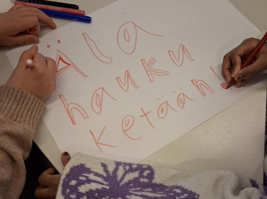 kahden lapsen kädet kirjoittavat lapulle älä hauku ketään. rasisminvastainen viikko koululla. suonenjoen yhtenäiskoulu.